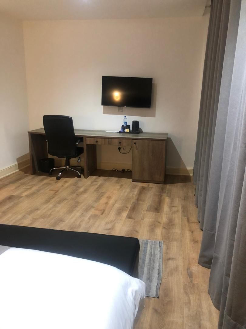 A hotel room with a bed, a desk, a chair, a television, and a wardrobe.