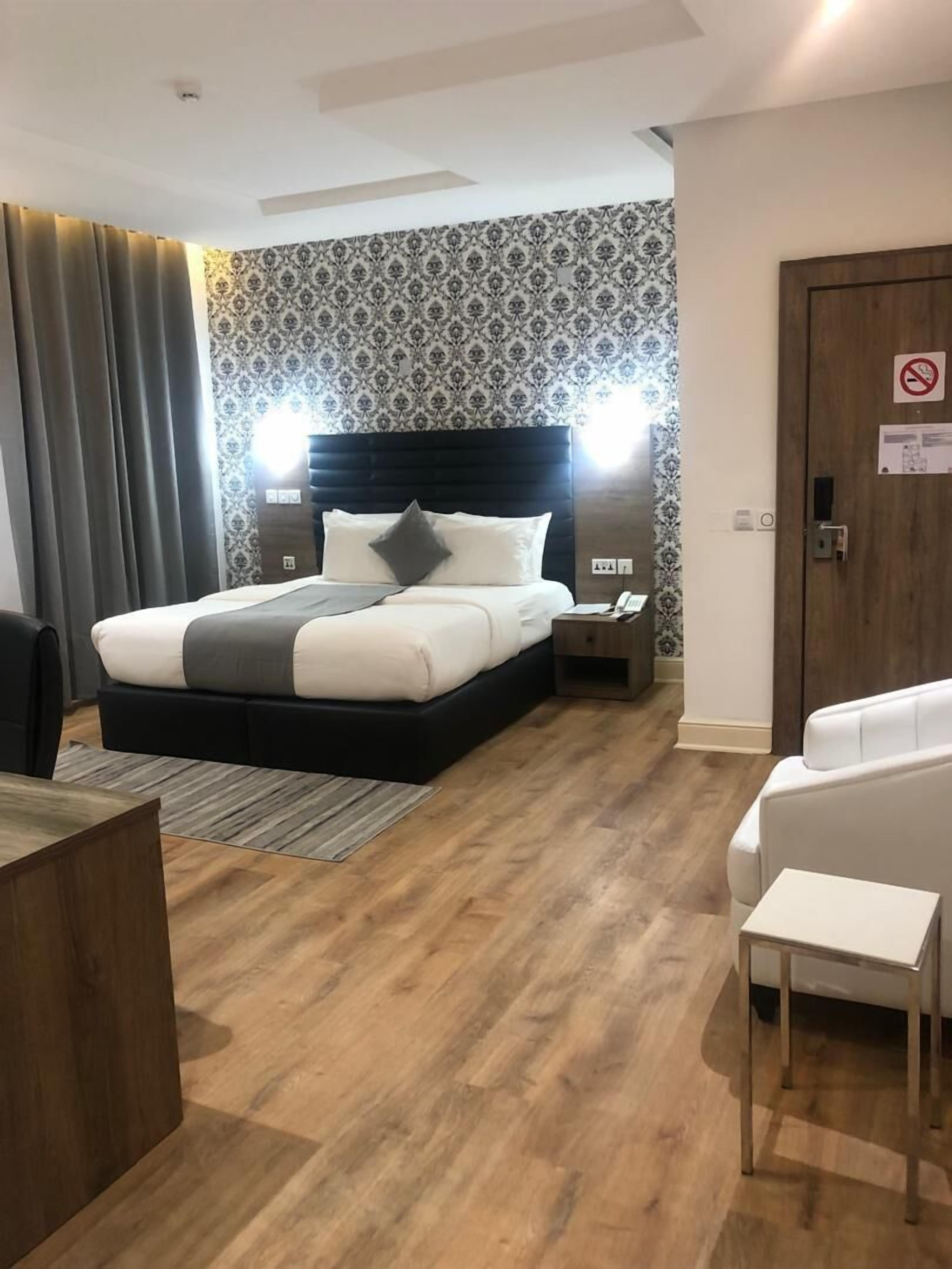 A modern hotel room with a large bed, bedside lamps, a desk, and a chair.