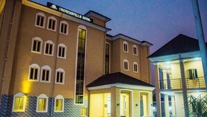 A multi-story hotel with a central entrance, multiple windows, and a sign indicating it is the Crownsville Hotel. - Crownsville Hotel - Airport Road (Ozuaha)