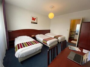 A hotel room with two beds, a desk with a laptop, and a door leading to a balcony.