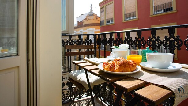Een balkon met een ontbijttafel, compleet met croissants, koffie en sinaasappelsap.