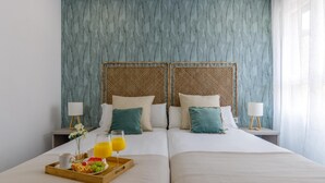 Un lit double avec un plateau de petit-déjeuner, deux tables de chevet et une fenêtre ornée de rideaux légers.