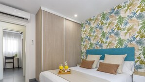 A hotel room with a bed, a breakfast tray, and a tropical wallpaper.