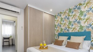 A hotel room with a bed, a breakfast tray, and a tropical wallpaper.