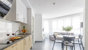 Una cocina moderna con comedor, que incluye una isla central, horno empotrado y un amplio ventanal que proporciona luz natural.
