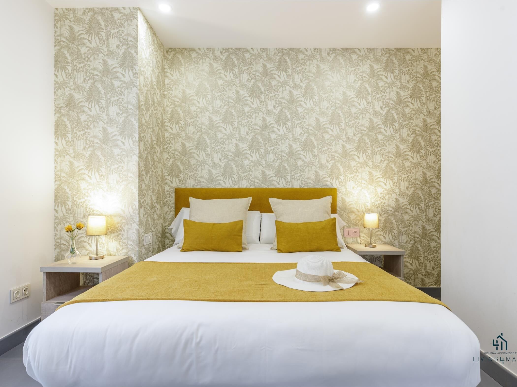 A hotel room with a large bed, two bedside tables with lamps, and a tropical wallpaper design.