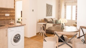 A compact living space with a kitchen area, a dining table, and a sofa.
