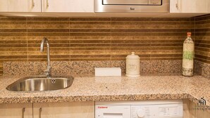 A kitchen with a stainless steel sink, a microwave, a Corbero dishwasher, and a granite countertop. - Mariblanca 1D Superior Living4malaga (Málaga)
