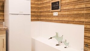 A kitchen with a white refrigerator, a chalkboard with 'Welcome' written on it, and a wall-mounted light fixture. - Mariblanca 1D Superior Living4malaga (Málaga)