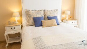 A neatly made bed with a white headboard, two bedside tables with lamps, and decorative pillows.