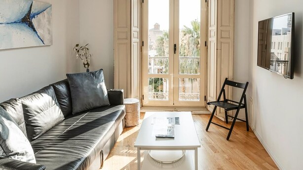 A modern living room with a leather sofa, a white coffee table, and a black chair.