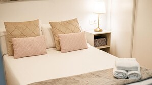 A neatly made bed with a quilted blanket, two pillows with a chevron pattern, and a folded towel on the bed.