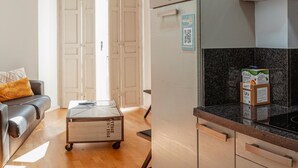 A modern kitchen with a microwave, oven, and a refrigerator. There is a cart with a QR code and a sign on the wall.