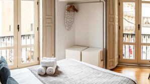 A hotel room with a bed, a small seating area, and a view of the city through large windows. - City Center Calderon 2201 Studio Living4malaga (Málaga)