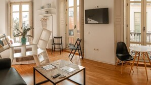 A modern living room with a glass coffee table, a sofa, a dining table with chairs, and a TV mounted on the wall. - City Center Calderon 2201 Studio Living4malaga (Málaga)