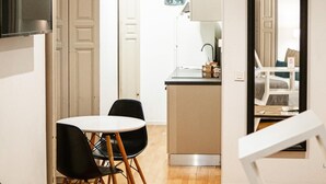 A compact kitchen with a sink, a small dining area with two chairs, and a refrigerator.