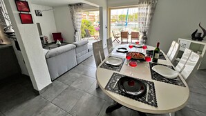 Ein Essbereich mit einem runden Tisch für vier Personen, einer Couch und Blick ins Freie.