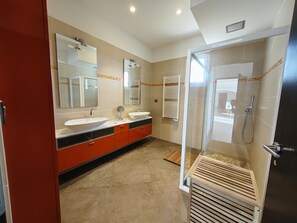 Features a dual sink vanity, heated towel rail, and glass-enclosed shower area.
