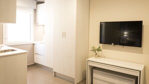 A modern kitchen with white cabinetry, a built-in TV, and a small plant on the counter.