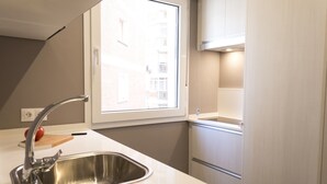 A modern kitchen with a stainless steel sink, a window, and built-in cabinets.