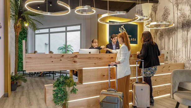 A modern reception area with wooden reception desks, a large plant, and a sign with the word "LAGA".