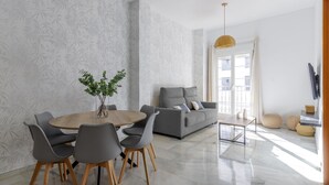 Un salon moderne avec un coin repas, comprenant un canapé, des fauteuils, une table basse et un vase avec des plantes.