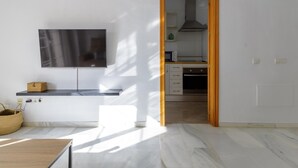 Une cuisine moderne dotée d’un téléviseur à écran plat, de meubles en bois et d’un sol carrelé.
