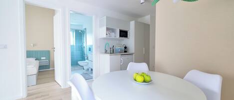 A modern kitchen with white cabinets, a microwave, and a sink.