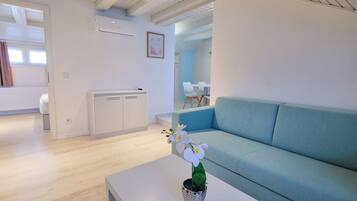 A modern living room with a sofa, a coffee table with a potted orchid, and a dining area with chairs and a table.
