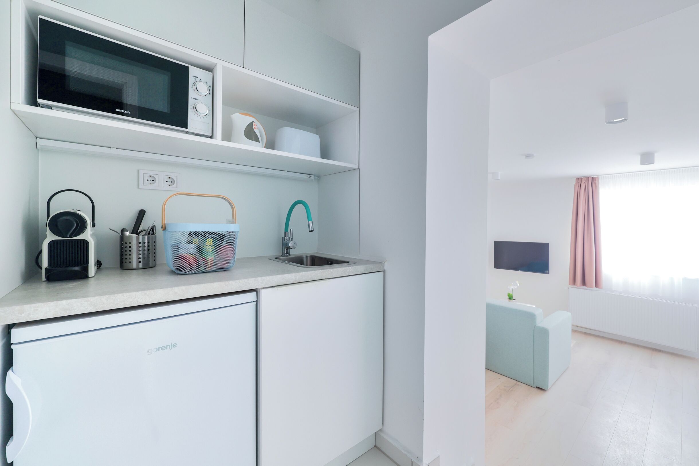 A modern kitchen with a built-in microwave, a sink, and a compact refrigerator.