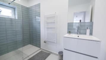 A modern bathroom with a glass shower enclosure, a white vanity with a mirror, and a towel rack.