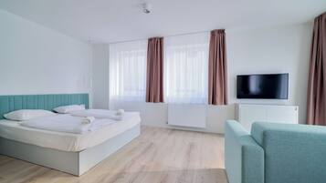 Quarto de hotel moderno com uma cama grande, uma televisão e um sofá.