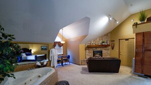 A spacious living room with a large fireplace, a cozy seating area, and a separate bedroom with a large window and a bed. - Branson White River Suite: A Private Forest Retreat (Reeds Spring)