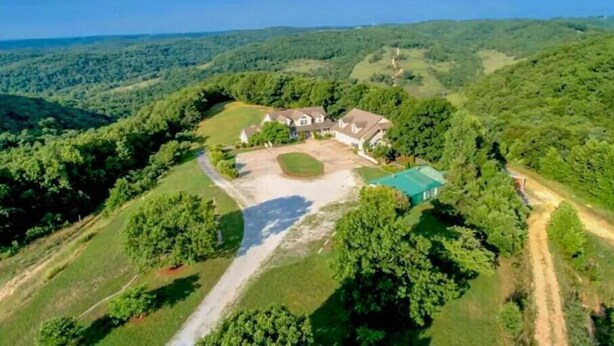 An aerial view of a large estate with multiple buildings, a tennis court, and surrounding lush greenery. - Branson White River Suite: A Private Forest Retreat (Reeds Spring)
