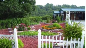 A garden with a white picket fence and a welcome sign. - Branson White River Suite: A Private Forest Retreat (Reeds Spring)