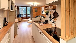 A modern kitchen with wooden cabinets, a built-in oven, and a large window overlooking a balcony.