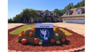 A welcome sign with a dove logo in front of a residential building with multiple garages. - Mountain Meadows Retreat - A Romantic Escape Overlooking the Ozark Mountains (Reeds Spring)