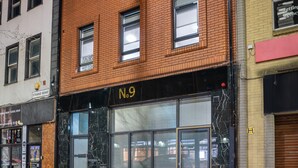 A multi-story building with a brick facade, numbered N.9, featuring large windows and a ground-floor storefront with a closed shutter. - Hotel No.9 (Londonderry)