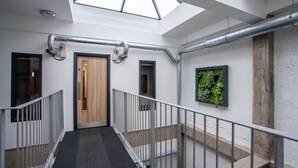 A modern interior with a skylight, metal railings, a wooden door, and a green wall feature. - Hotel No.9 (Londonderry)