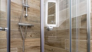 A shower with a glass door, a handheld showerhead, and a wall-mounted control panel. - Hotel No.9 (Londonderry)