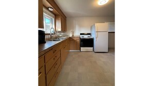 Una cocina compacta con armarios de madera, horno empotrado y refrigerador.