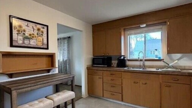 Una cocina con armarios de madera, una encimera, un fregadero y una ventana.