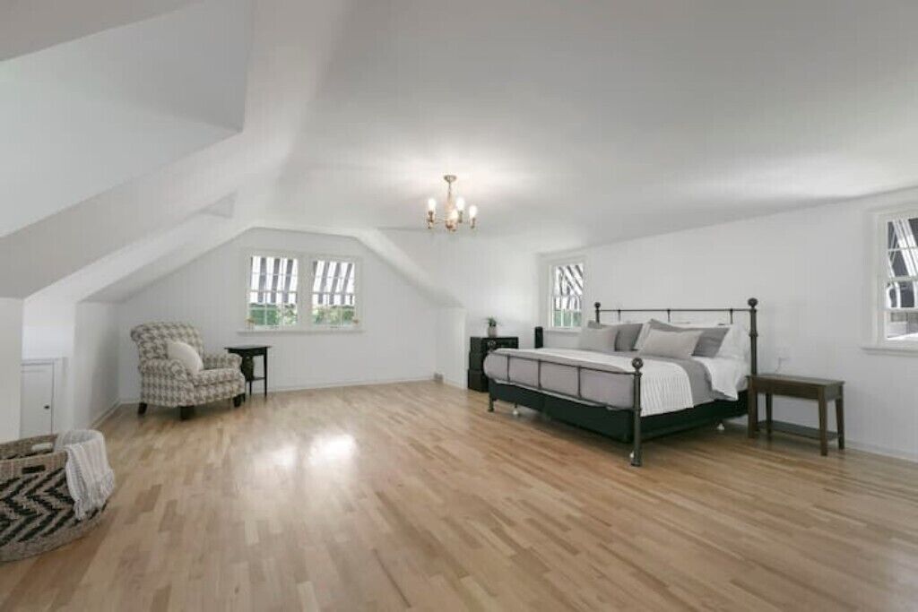 A bedroom with a bed, a chair, a nightstand, and a chandelier.