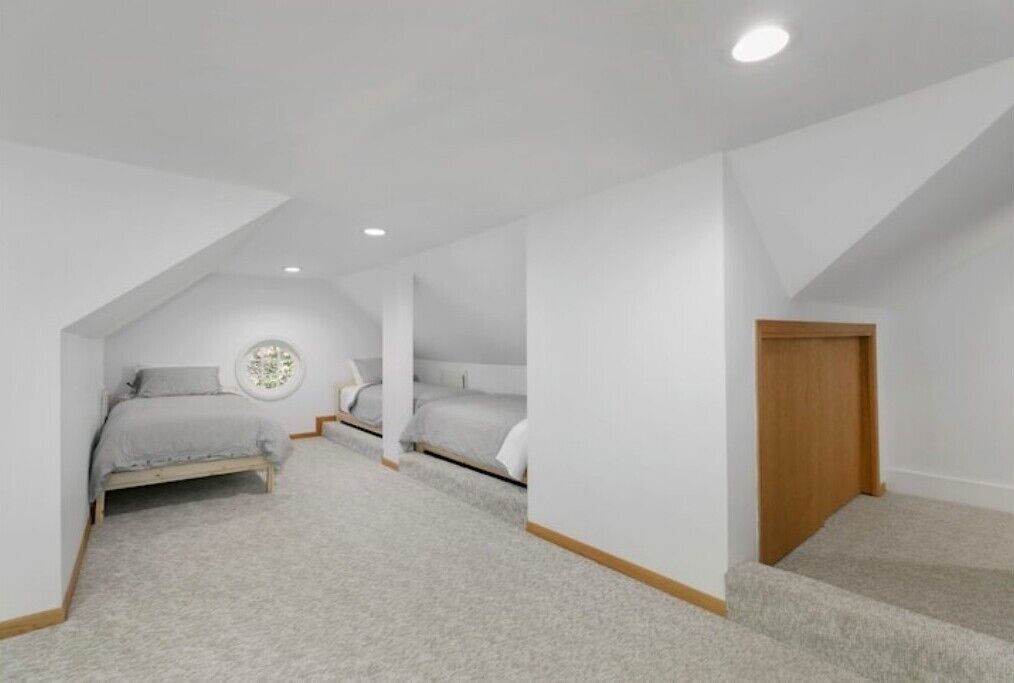 A bedroom with a single bed, a small bedside table, and a door leading to another room.
