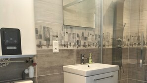 A modern bathroom with a toilet, sink, and shower. - Terrace apartment in Merlimont (Merlimont)