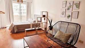 A modern living room with a bed, a black chair, a wooden coffee table, and a bookshelf. - Large Apartment Villa Urquiza (Buenos Aires)