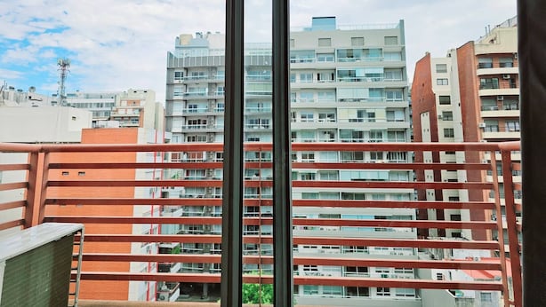 A view from a balcony with a metal railing, overlooking a multi-story residential building with balconies and windows. - Large Apartment Villa Urquiza (Buenos Aires)