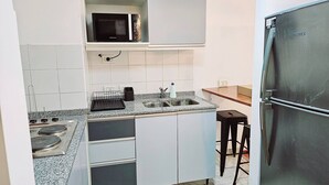 A compact kitchen with a microwave, sink, and a refrigerator. - Large Apartment Villa Urquiza (Buenos Aires)