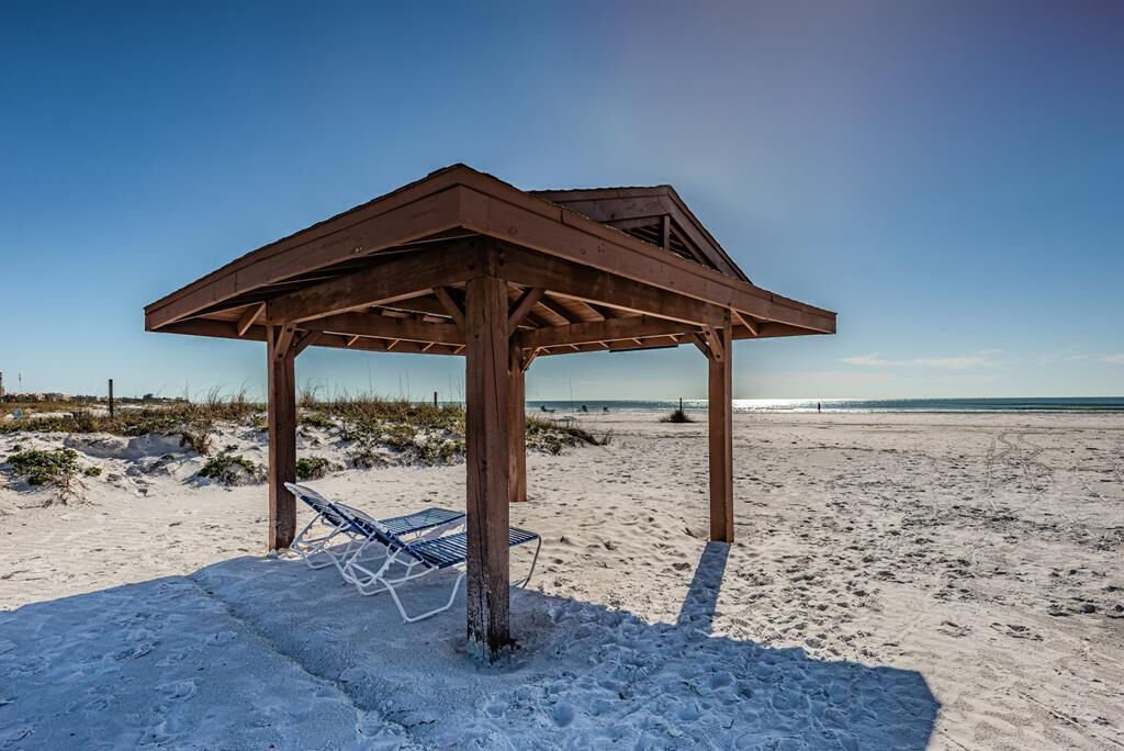 Een houten strandgazebo met een enkele ligstoel.