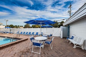 A pool area with lounge chairs, a table, and umbrellas.
